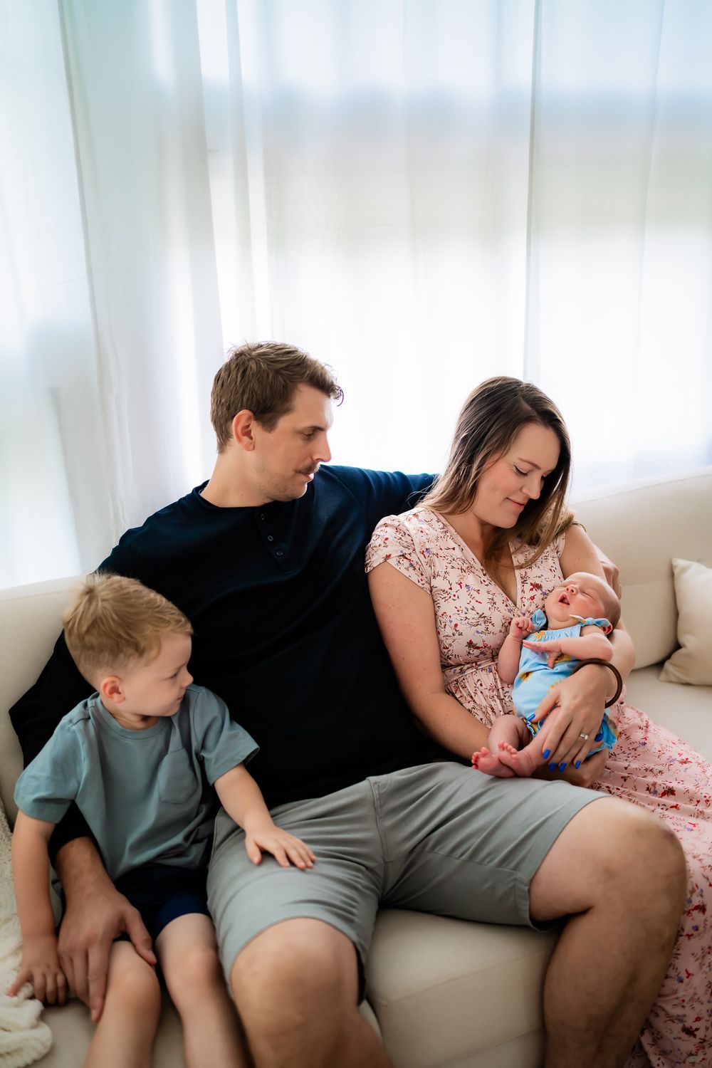 A family relaxes together on a white couch in a series of connected tender moments.