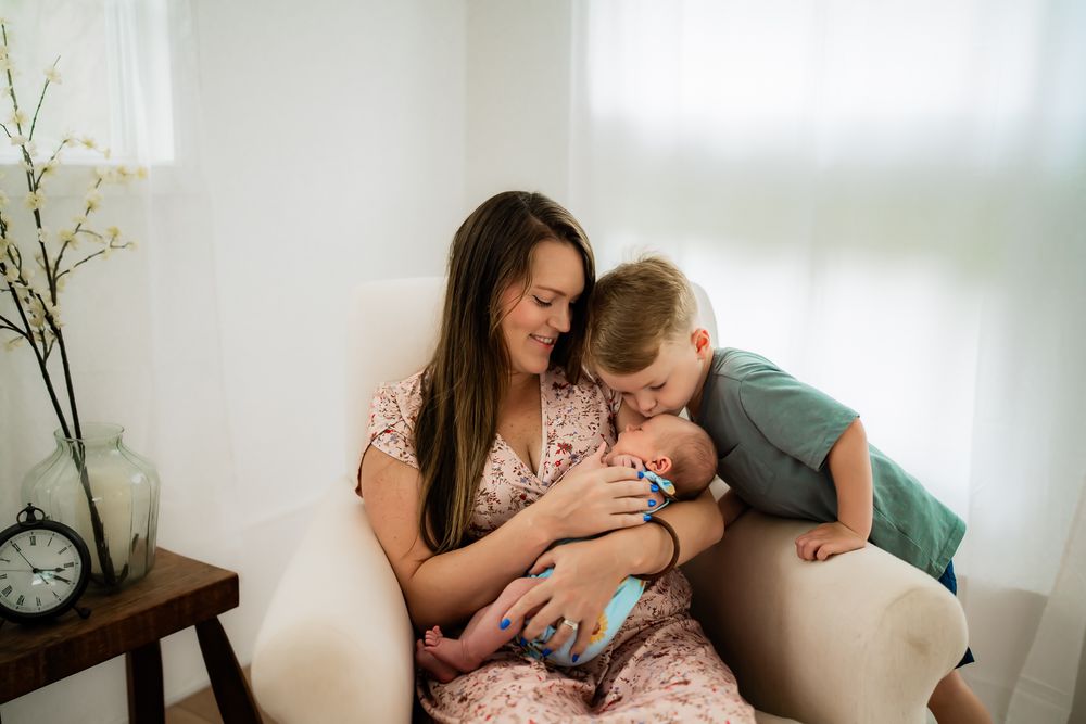 A tender family moment shared between parents and newborn baby in a bright, naturally lit room.