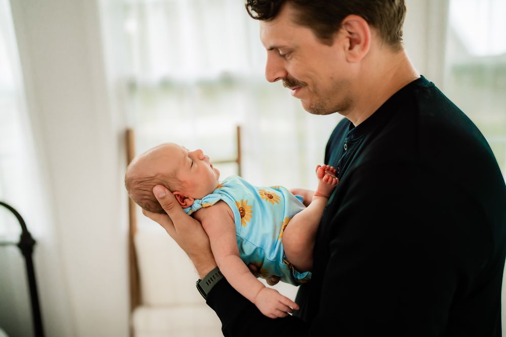 Healthcare worker in protective gear cradles and feeds a premature infant in a hospital setting.