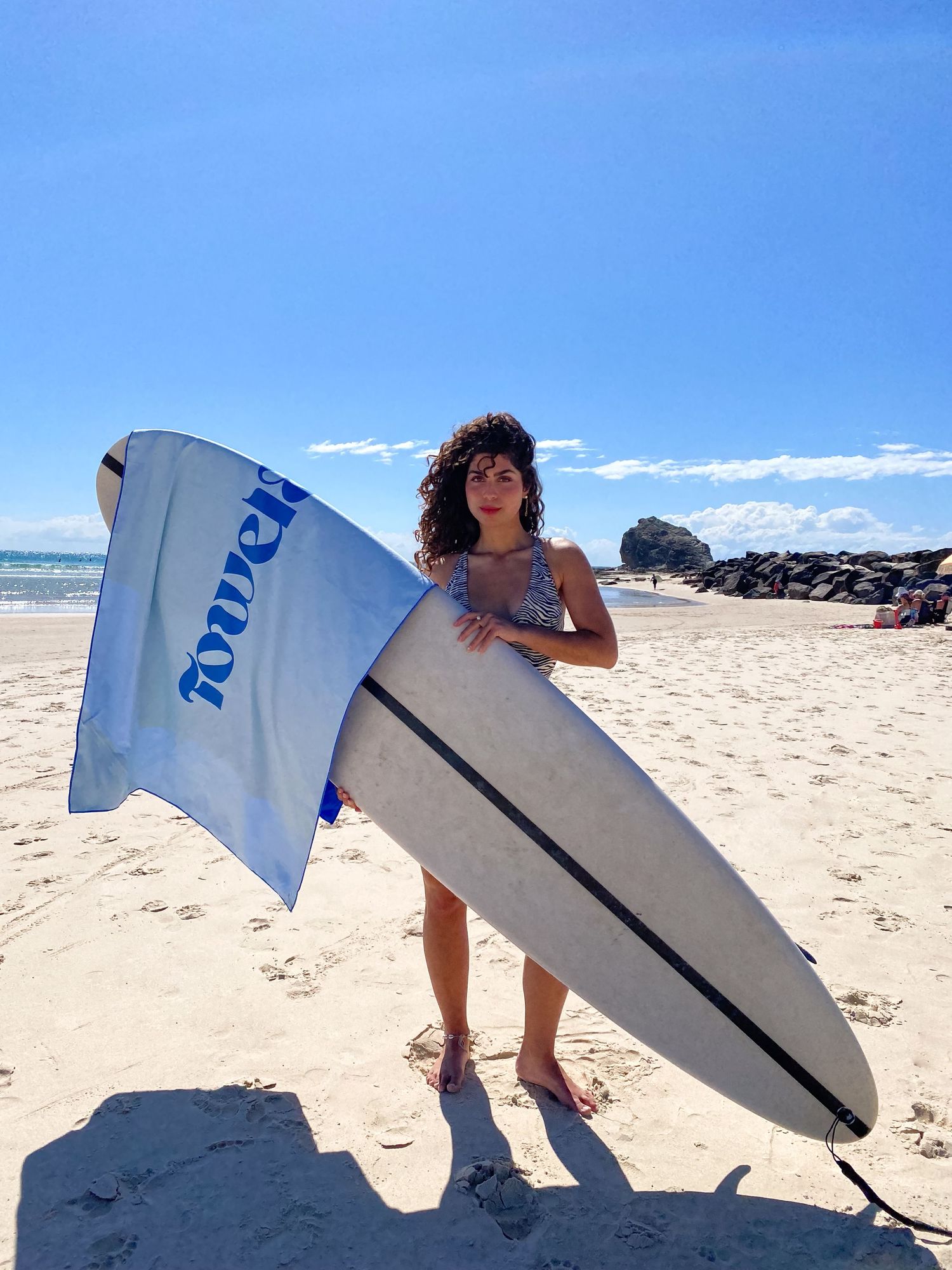 A sequence of images showing a windsurfer carrying and balancing a large surfboard across an empty sandy beach.