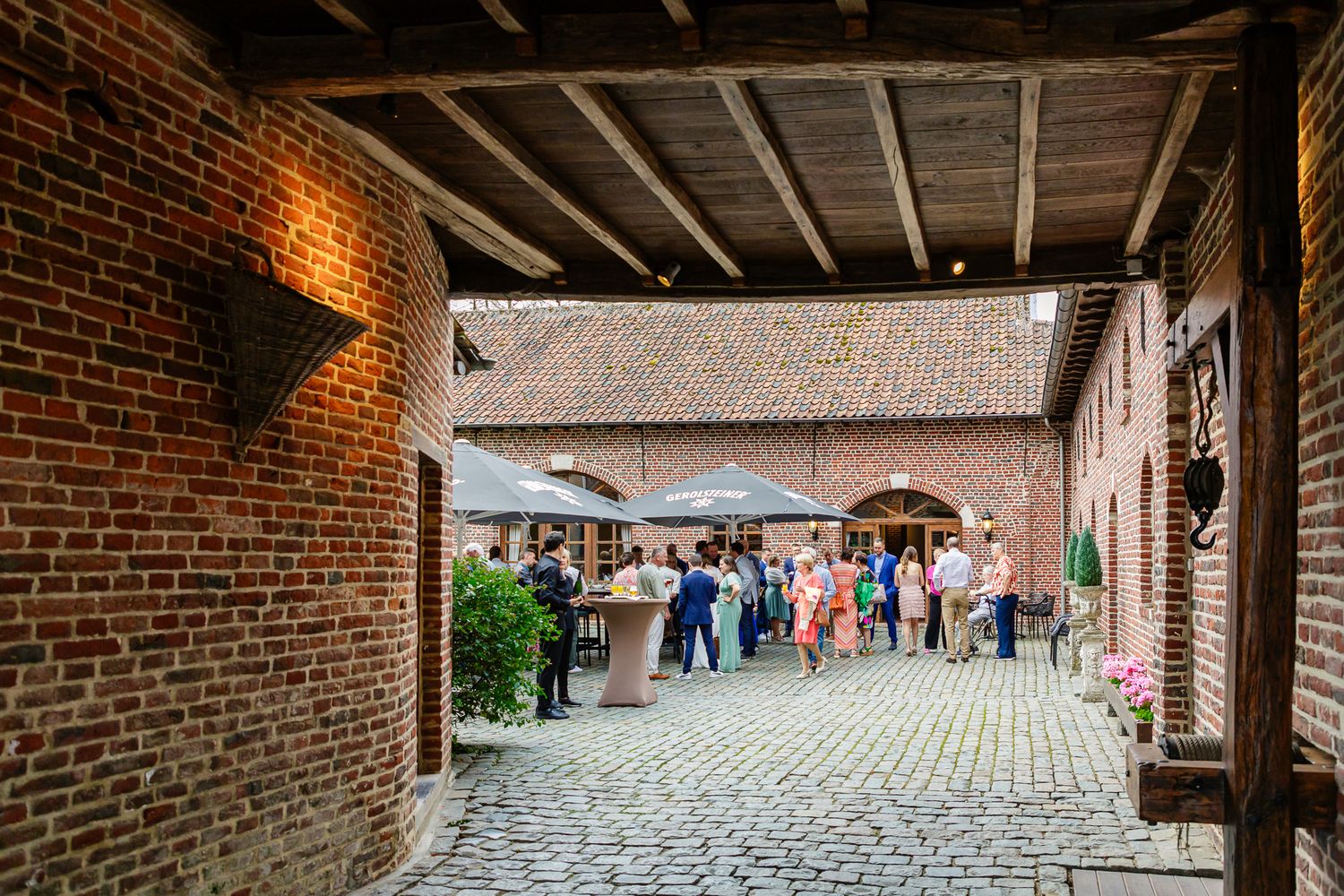 Wide panoramic view of a rustic brick pathway under covered walkway arches at a historic site in warm lighting.