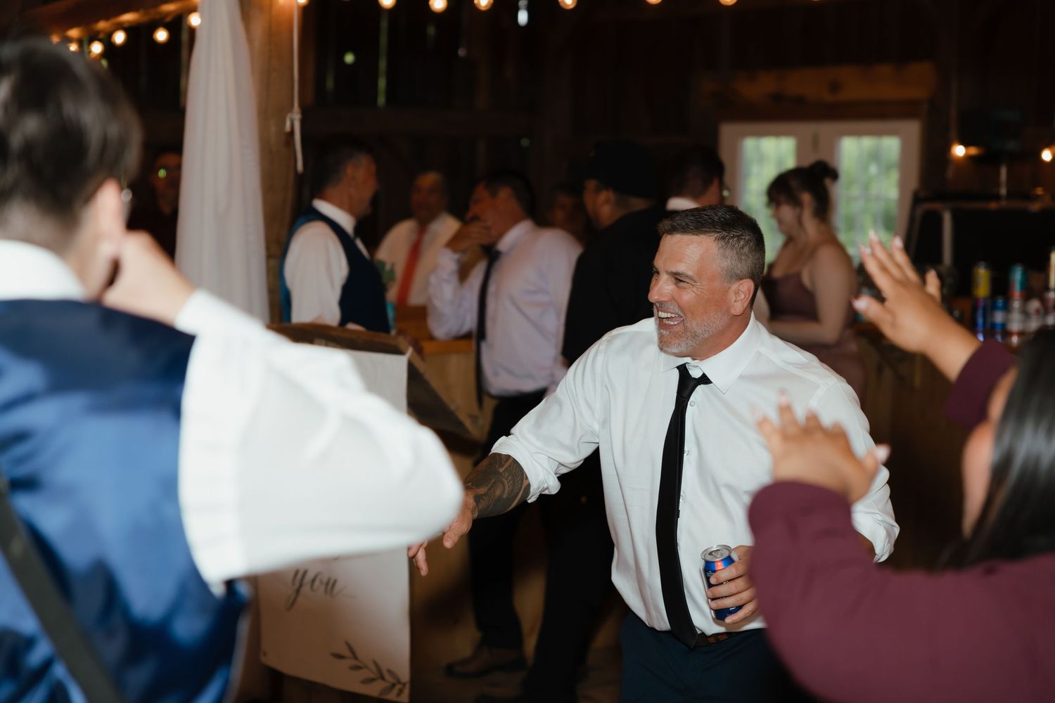 Dancing couples twirl beneath twinkling lights at an evening wedding reception celebration.
