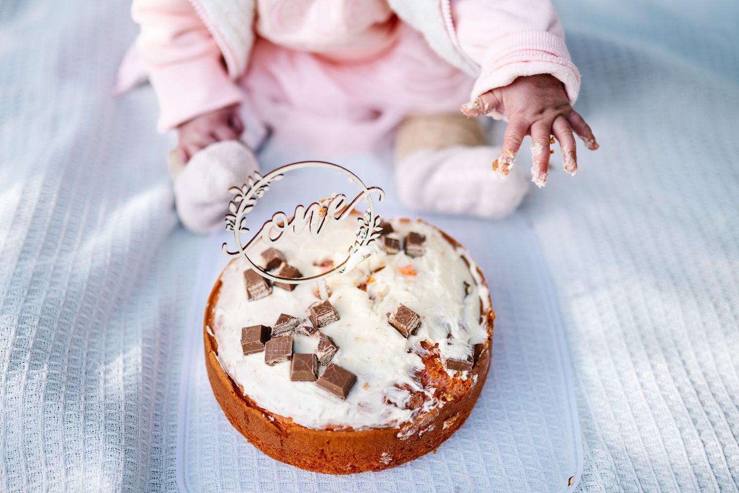 Baby's hands covered with cake while celebrating her one year old birthday with a cake smash mini photo session in Melbourne.