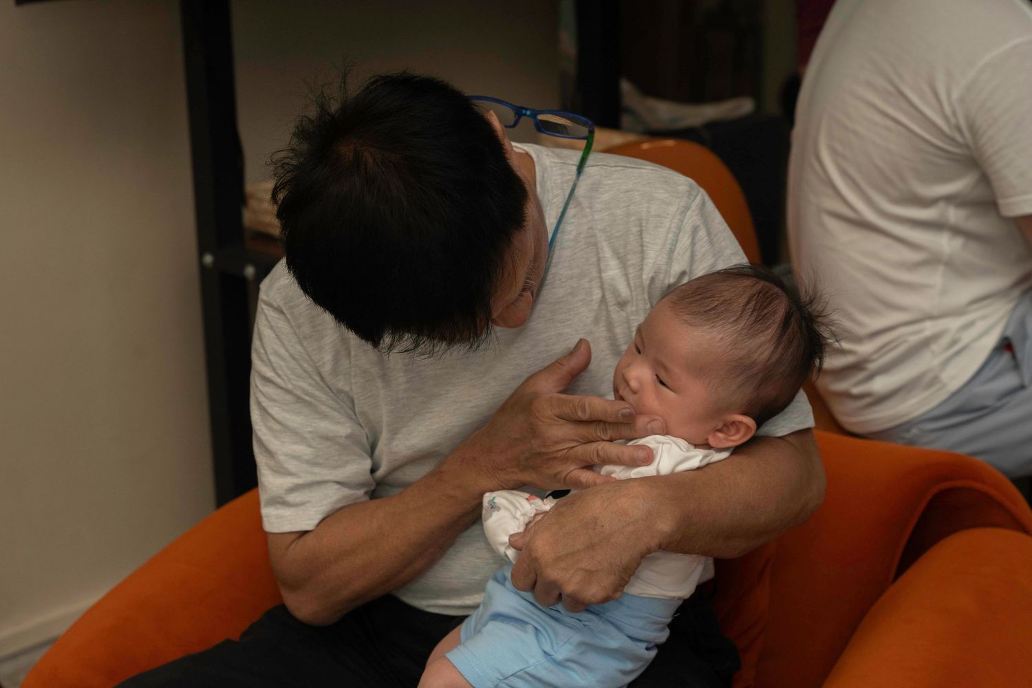 Baby being held on an orange sofa while spending time with family.