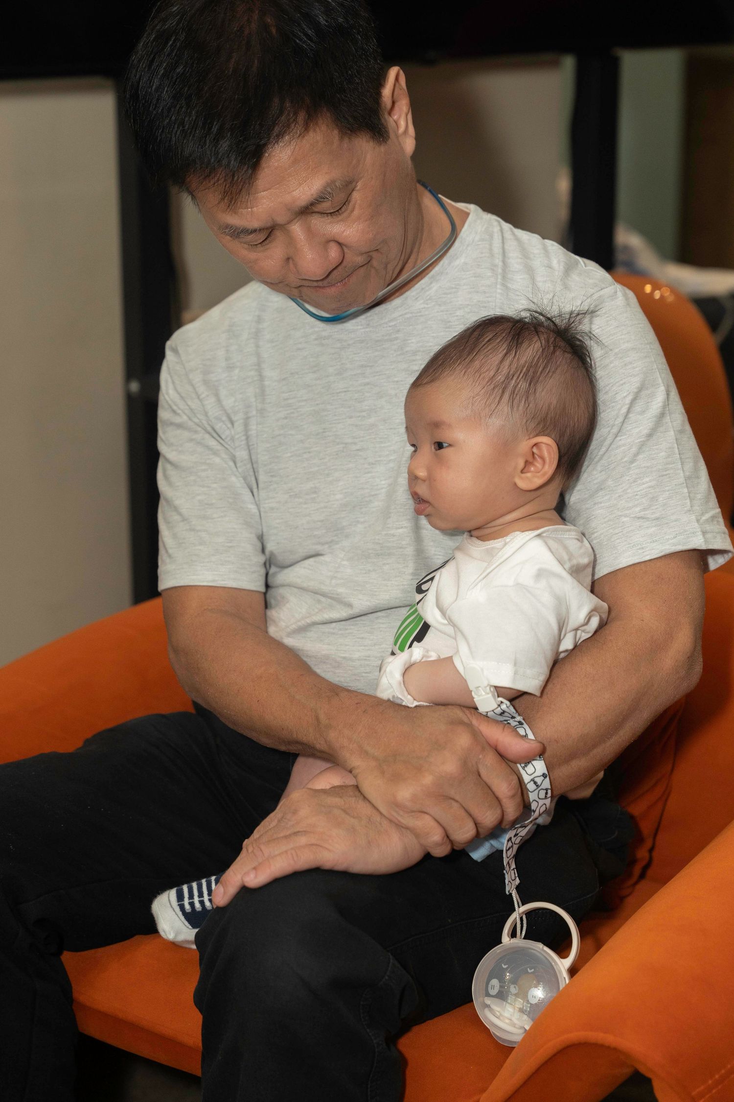 Quiet moment with an infant on an orange armchair during a peaceful afternoon.