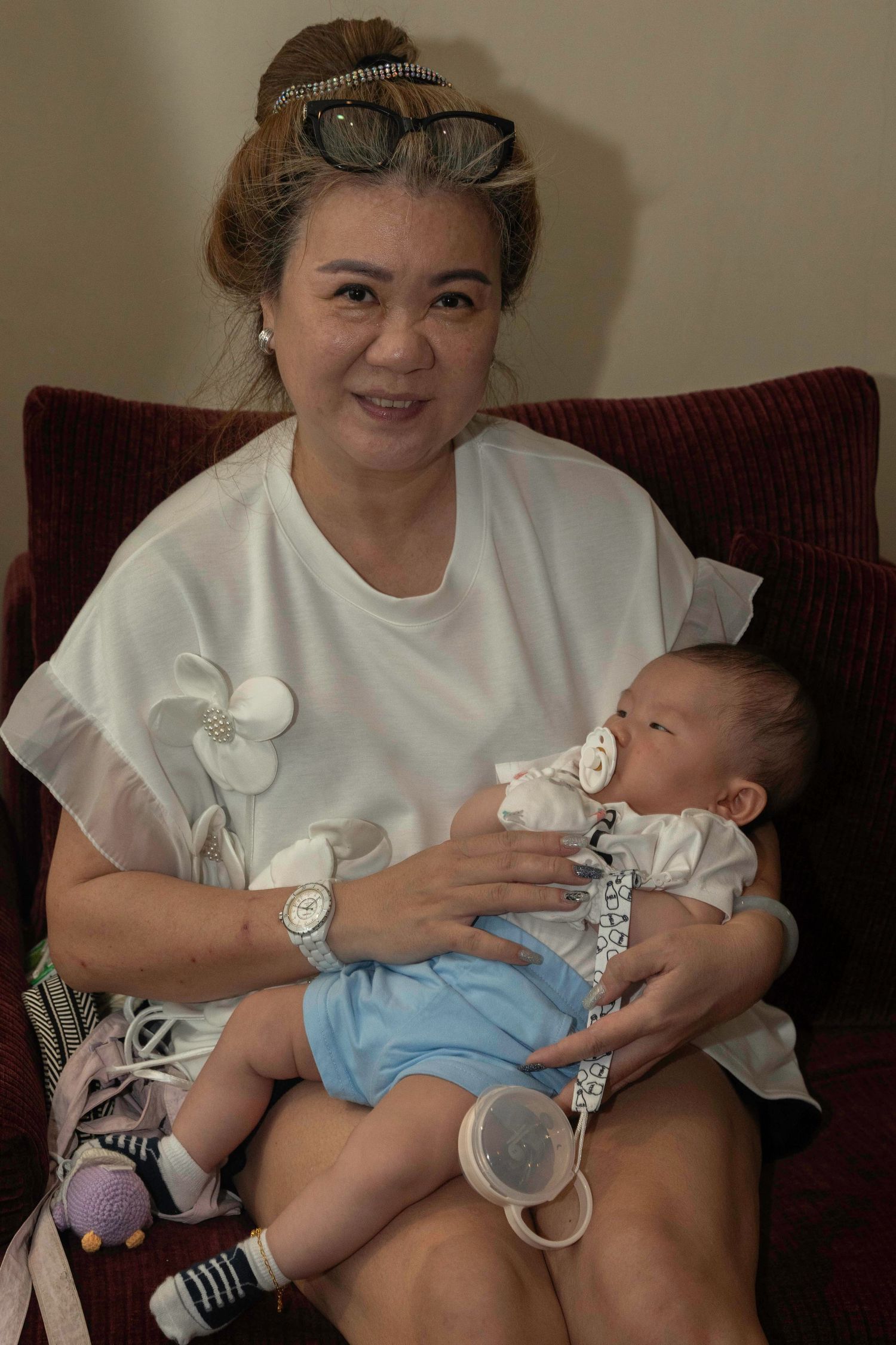 A series of photos show an adult holding and cradling a sleeping baby wearing a blue outfit and white bib.