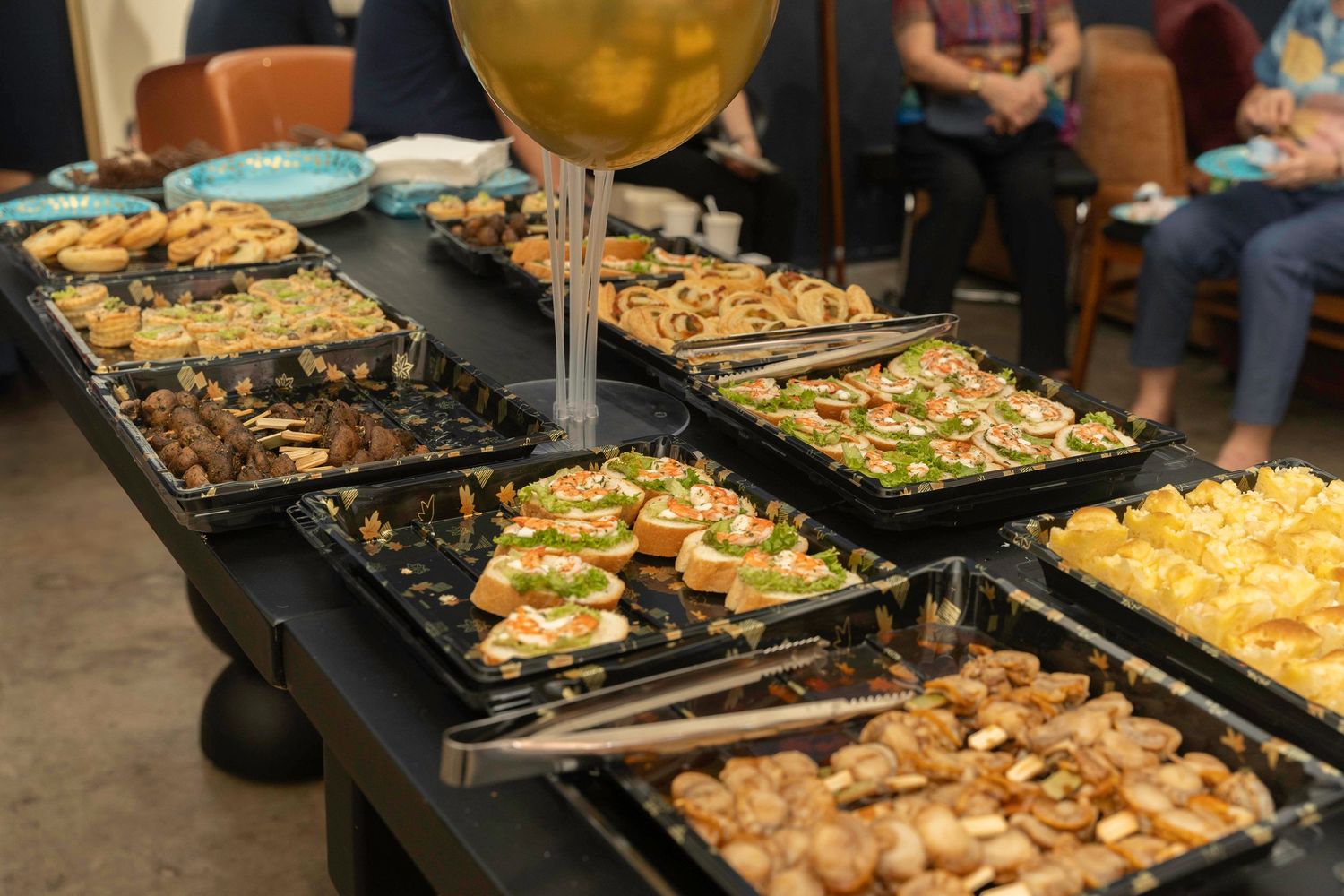 Catering buffet with multiple chafing dishes filled with various hot foods and side dishes served at an event.