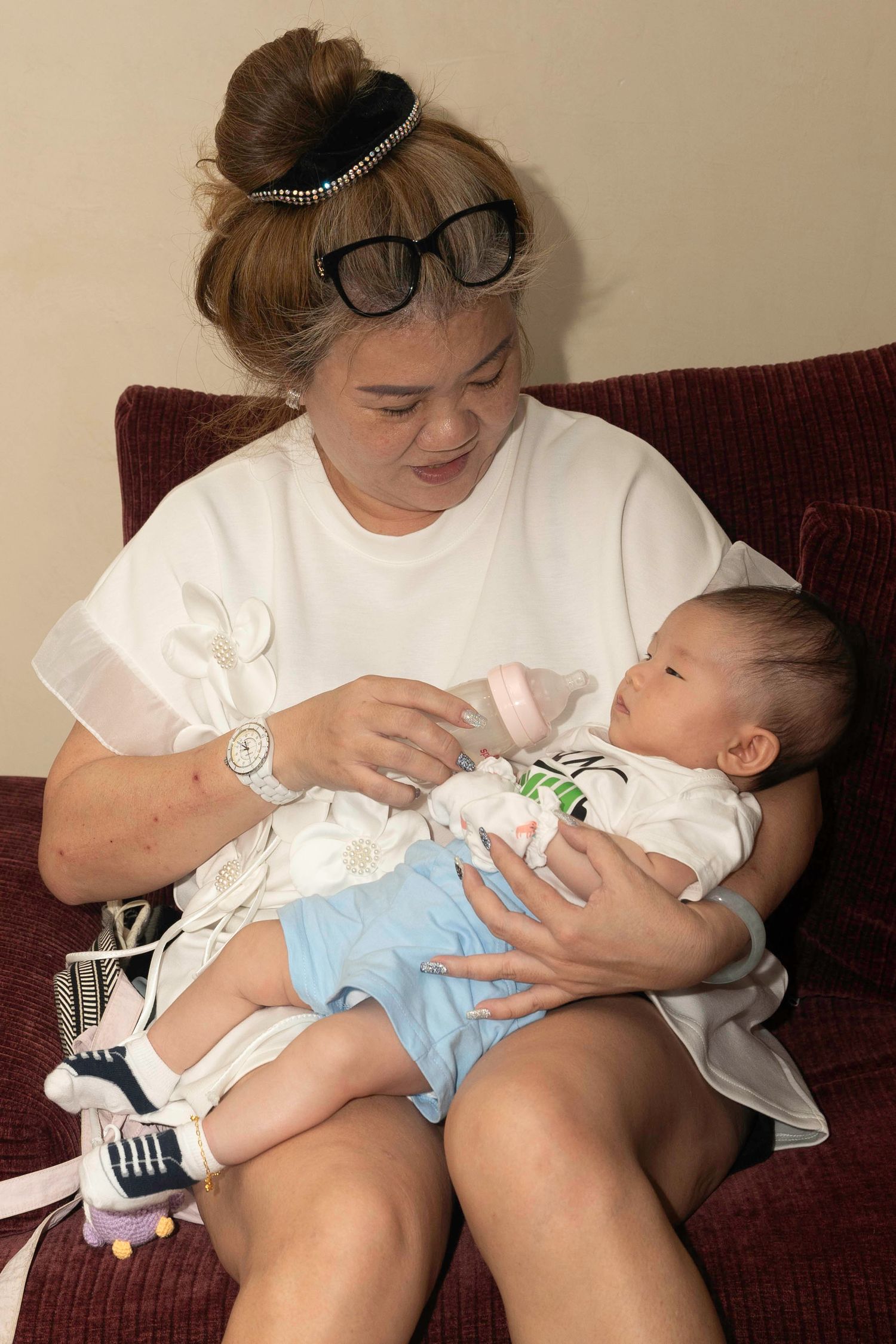 A series of photos showing an infant being bottle-fed while being cradled on a brown couch.