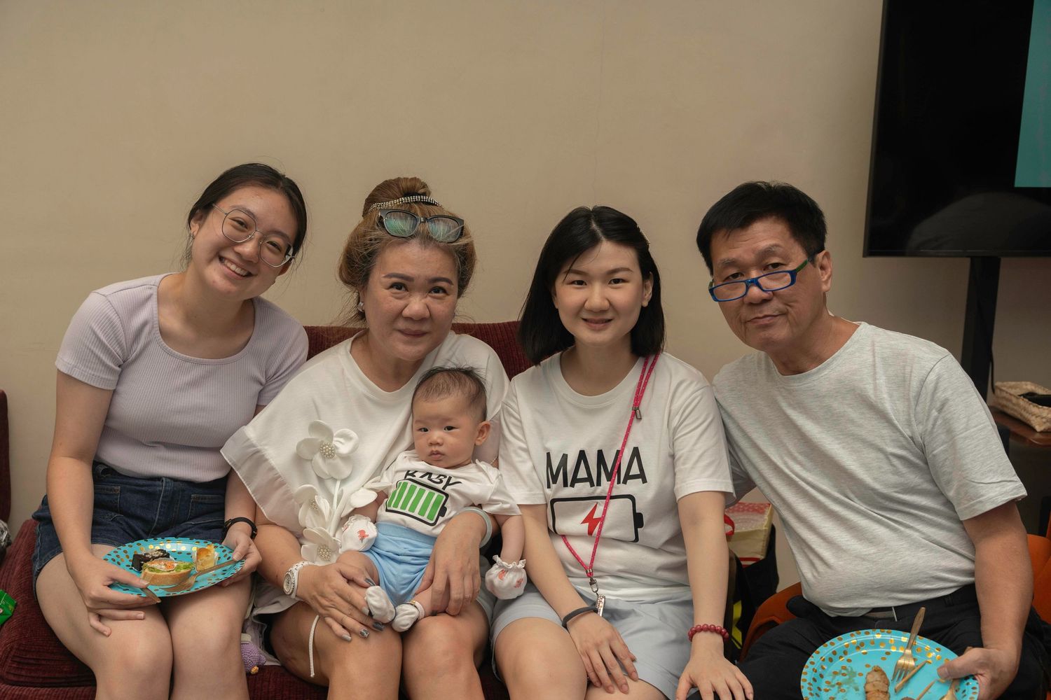 A joyful family gathering with multiple people seated together smiling and socializing at a casual indoor event.