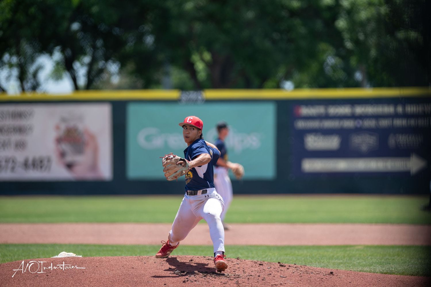 Softball pitcher in red and black uniform winding up to throw.