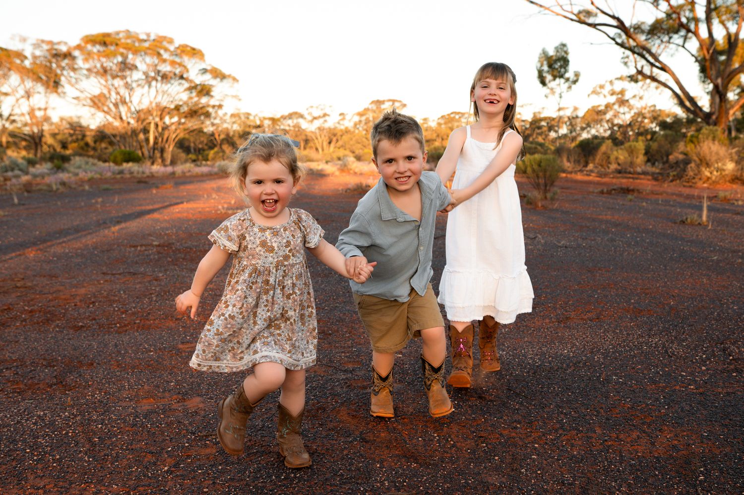 Children stroll along a rustic path at sunset during a golden hour outdoor family photo session.