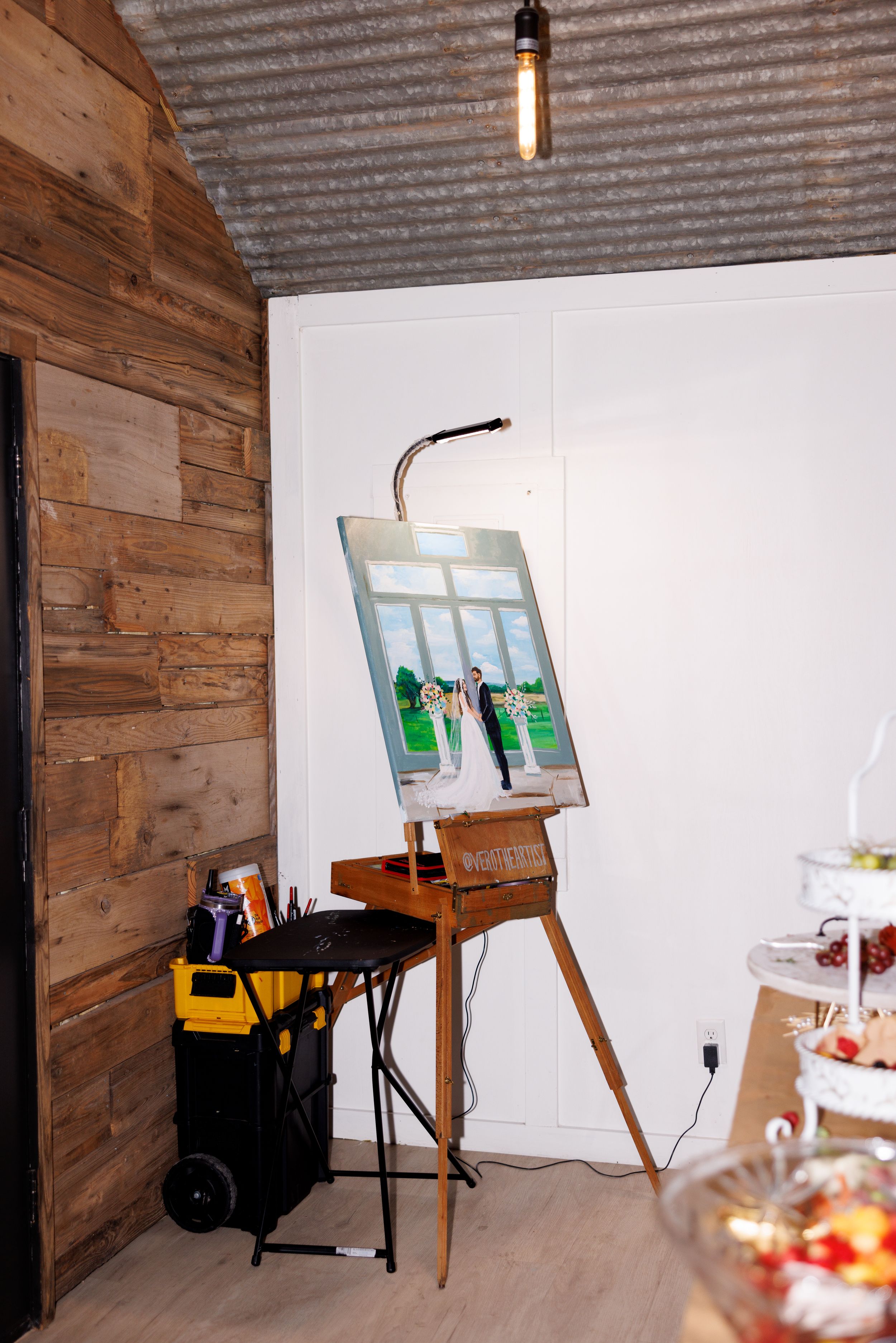 Rustic venue setup with wooden walls and easel displaying wedding photos.