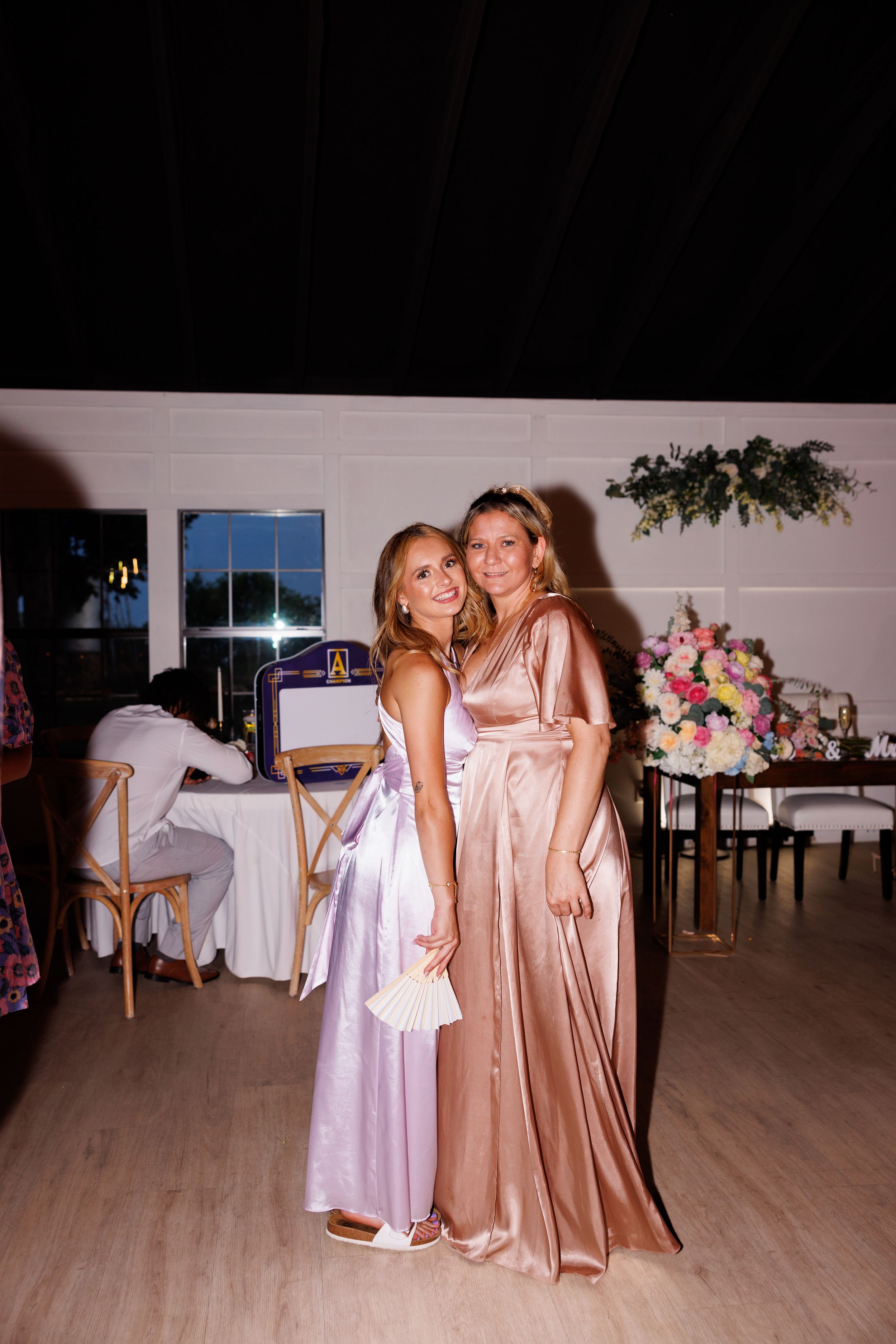Wedding party members in pink and white dresses dance together on a wooden dance floor.