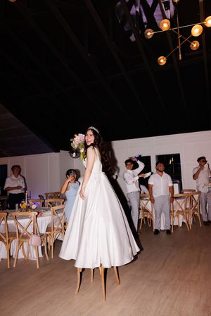 Wedding reception venue with wooden chairs and white decor under string lights.