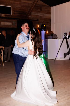 Dancing couples celebrate on the wooden dance floor at a wedding reception.
