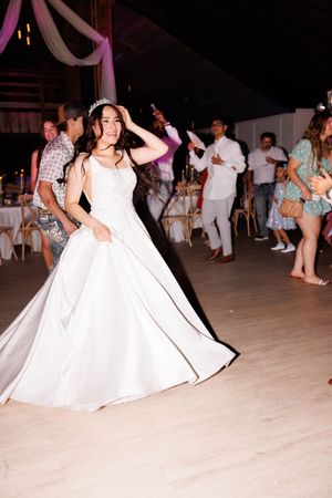 Wedding guests dance in formal attire on a light-colored dance floor.