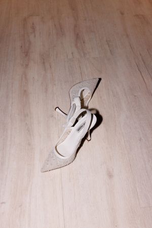 White bridal shoes scattered on a light wooden floor.