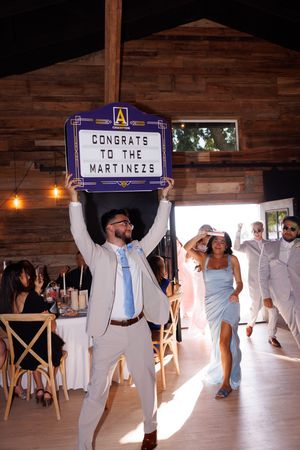 Wedding guests hold up congratulatory signs while dancing at an indoor reception.