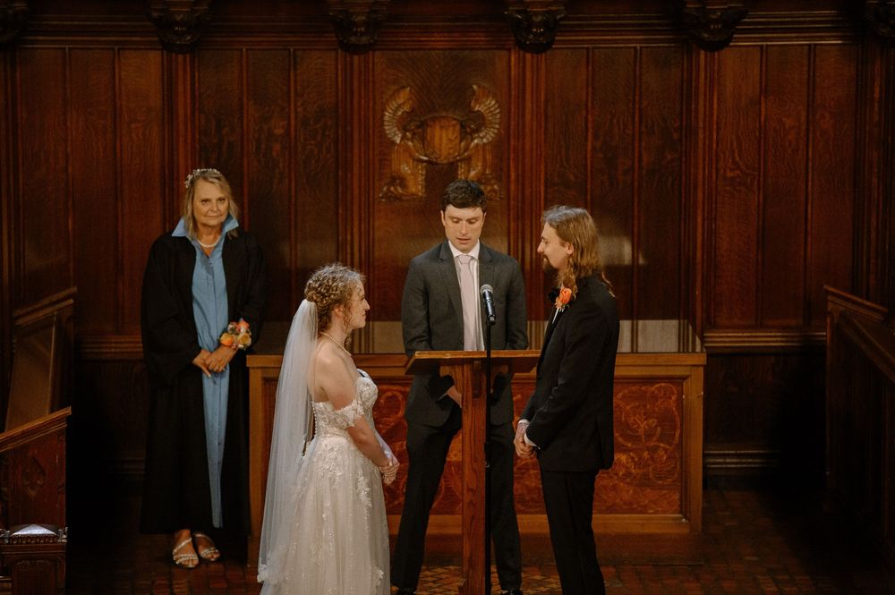 A wedding ceremony takes place in a grand wooden-paneled church with warm lighting and traditional decor.