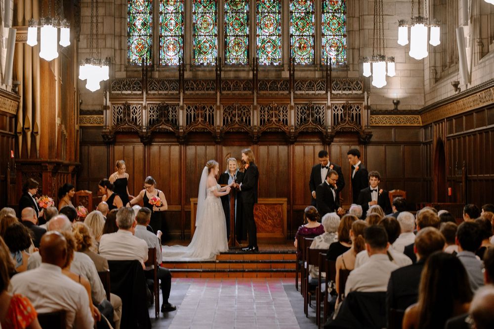 An elegant church wedding ceremony with wooden paneling and stained glass windows illuminating the sacred space.
