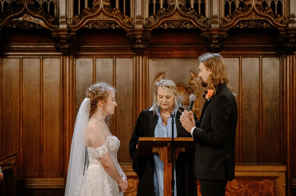 A group gathers in a stunning wooden-paneled church interior during an emotional wedding ceremony.