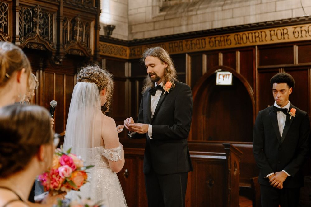 A wedding ceremony takes place in a historic wooden church with ornate paneling and decorative details.
