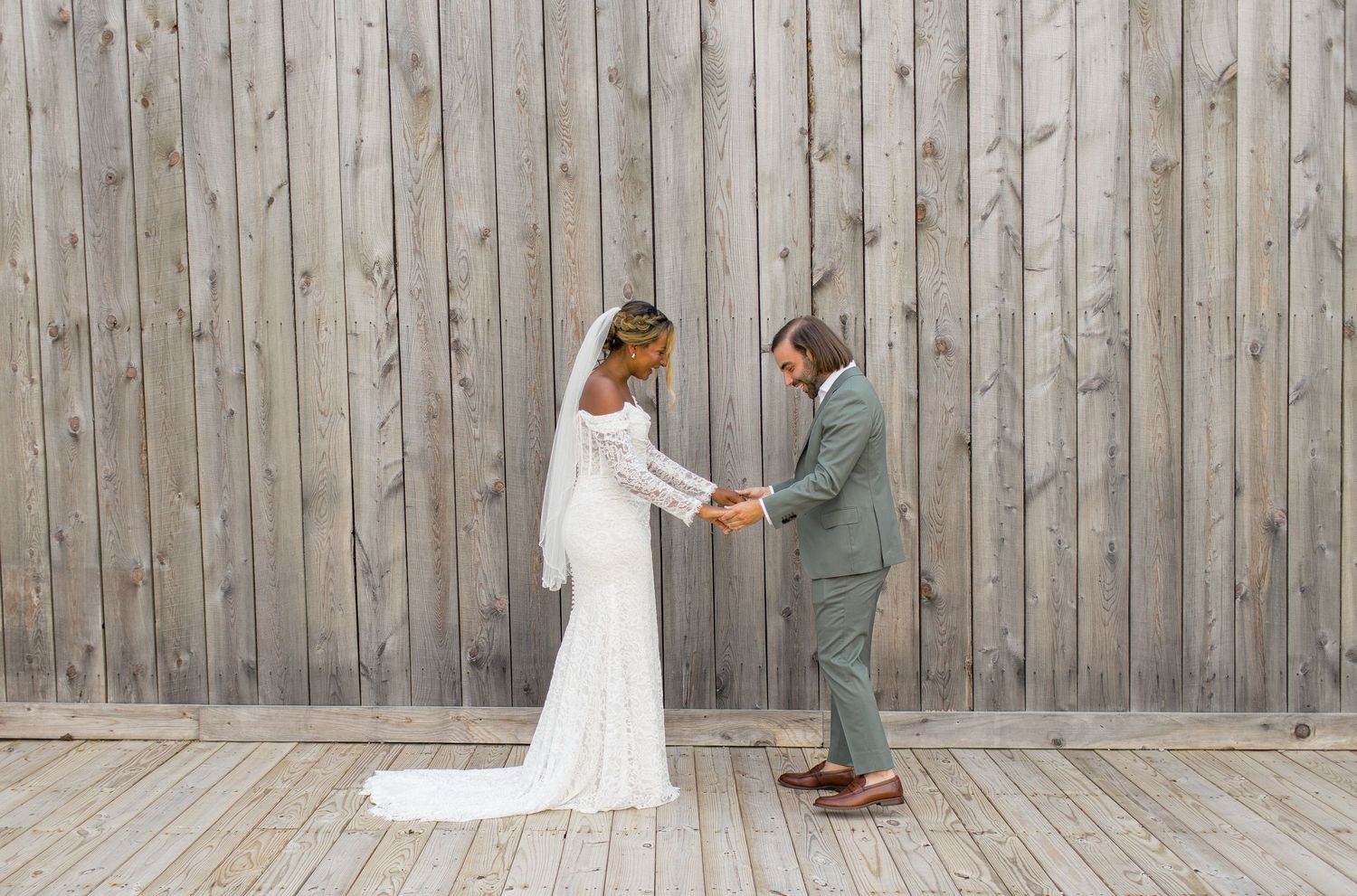 A bride and groom share an intimate moment against a rustic wooden wall during their wedding day.