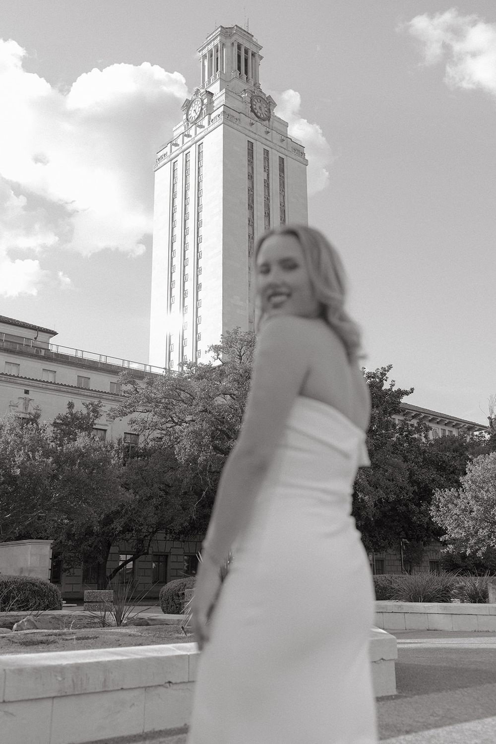 Black and white photo showing the University of Texas Tower with figure in white dress in foreground.