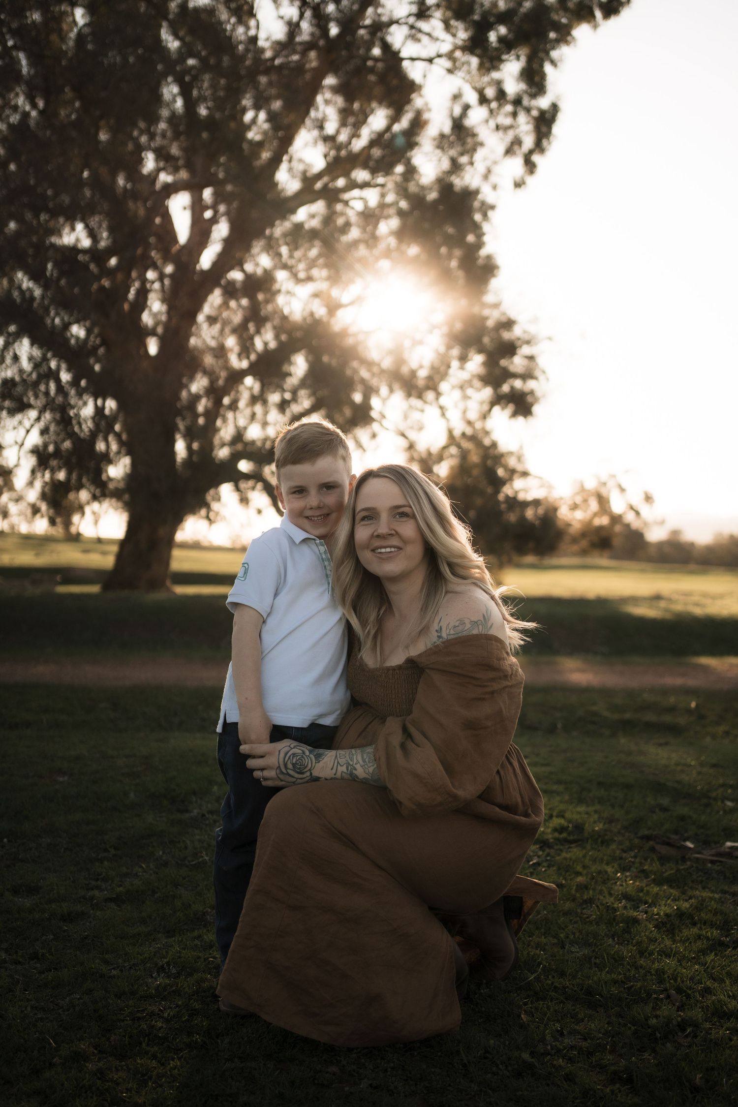 Golden hour portrait session in a grassy field with backlit sunlight creating a dreamy atmosphere.