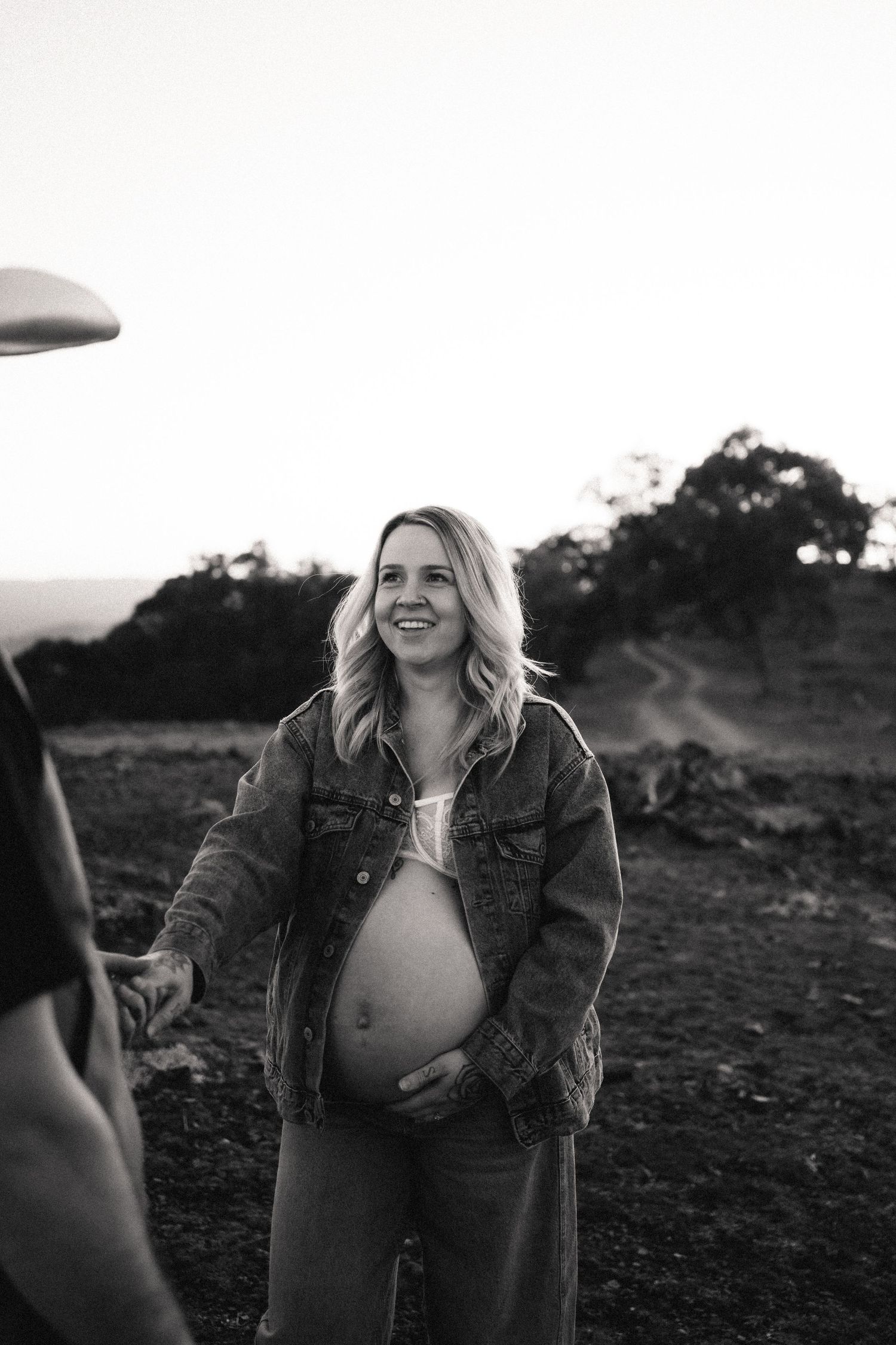A joyful maternity photo session captured in black and white outdoors.