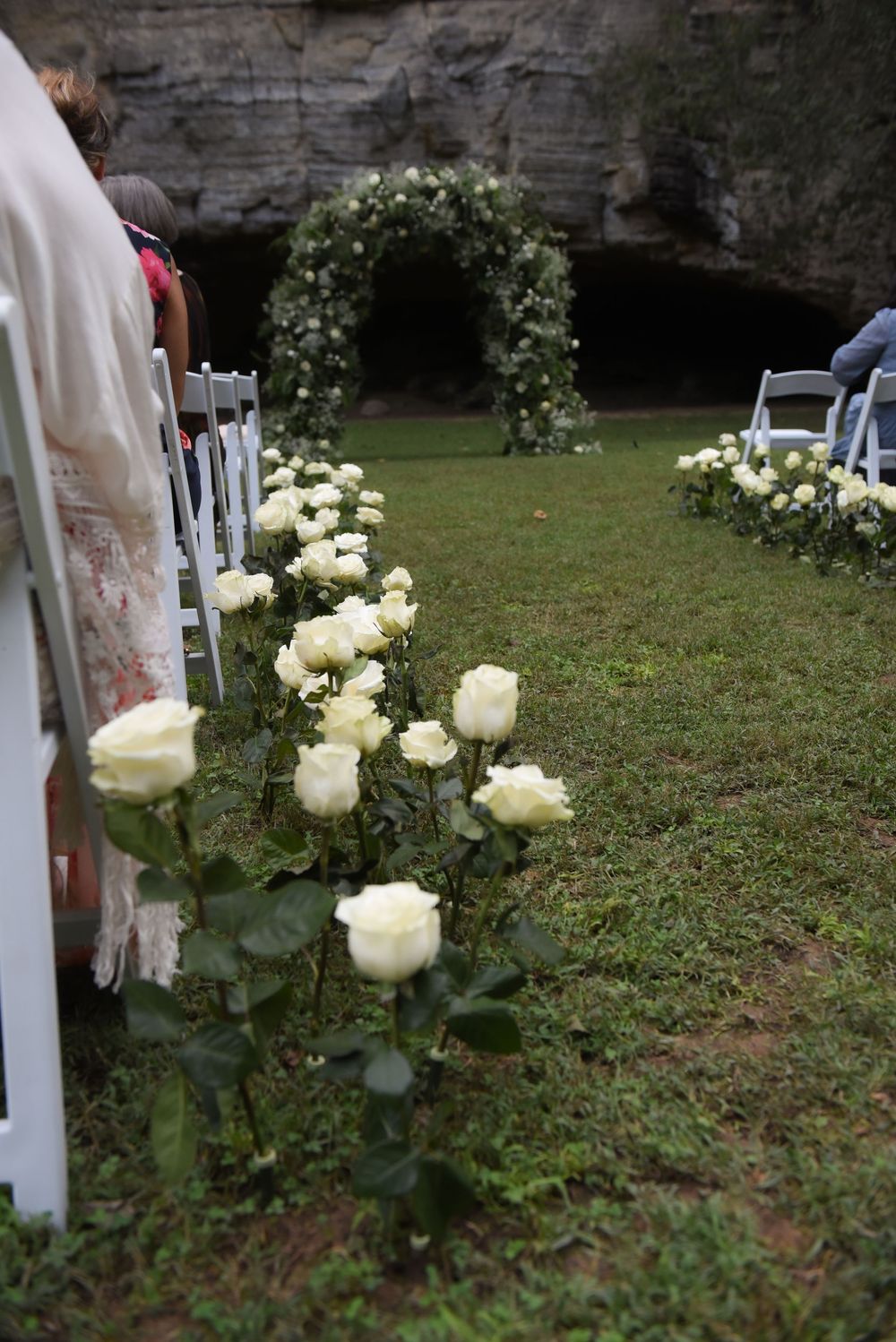 White roses line a garden path creating an elegant outdoor wedding aisle display.