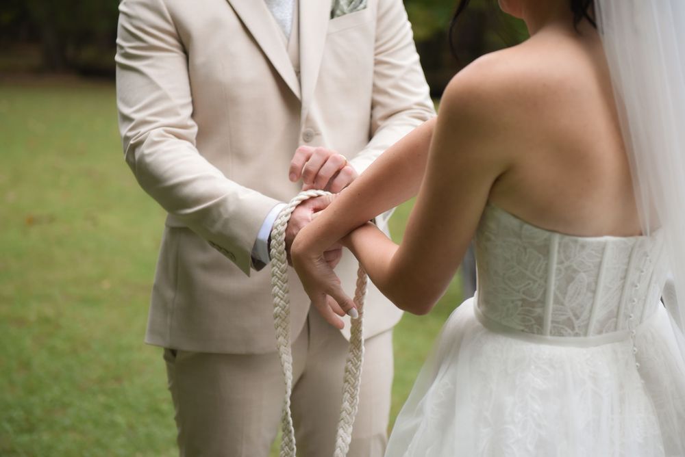 An elegant outdoor wedding ceremony moment captured with flowing white dress details.