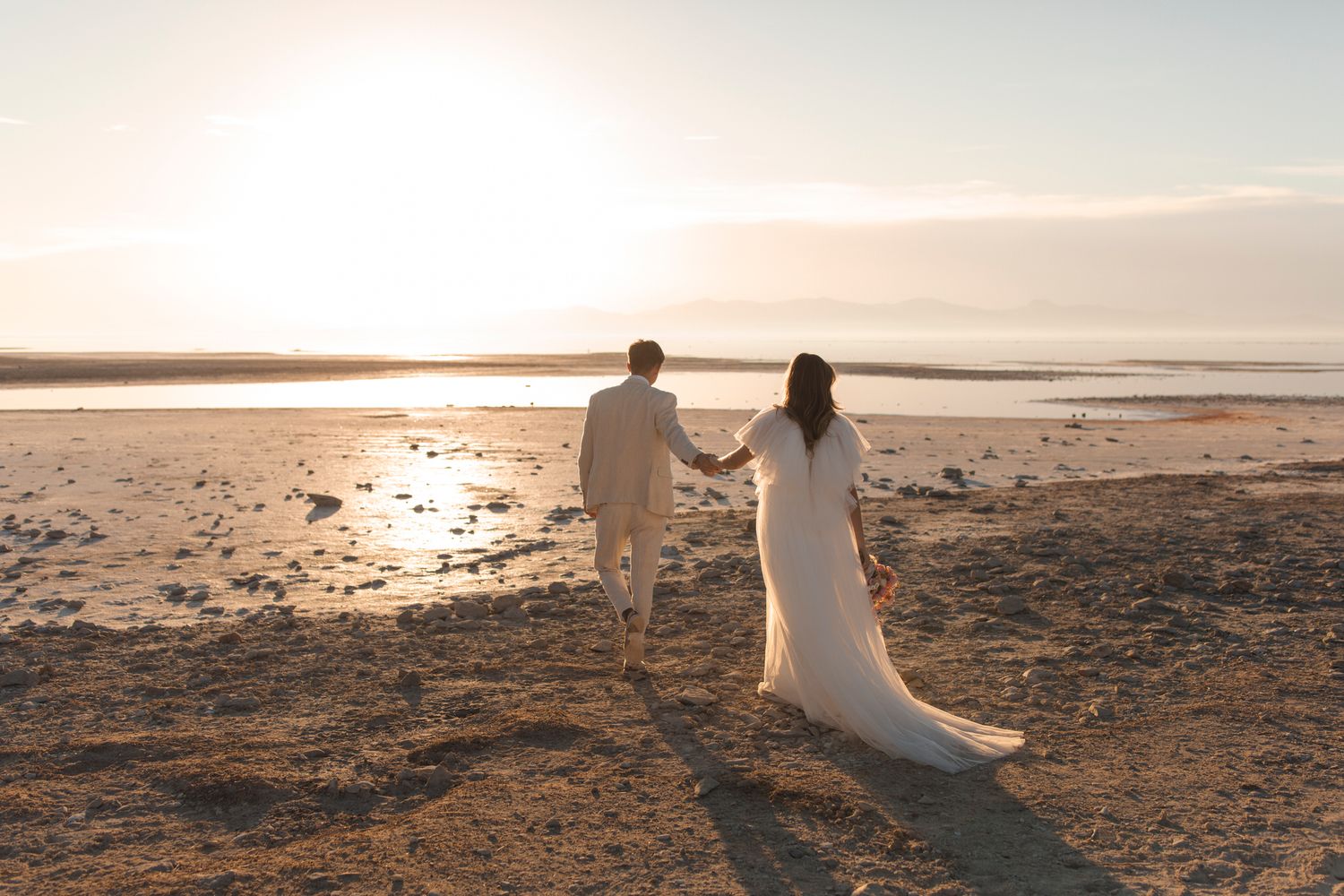 Couple walk along the beach in wedding attire. How thoughtful visuals drive conversations. Content strategy. Lumenali Photo