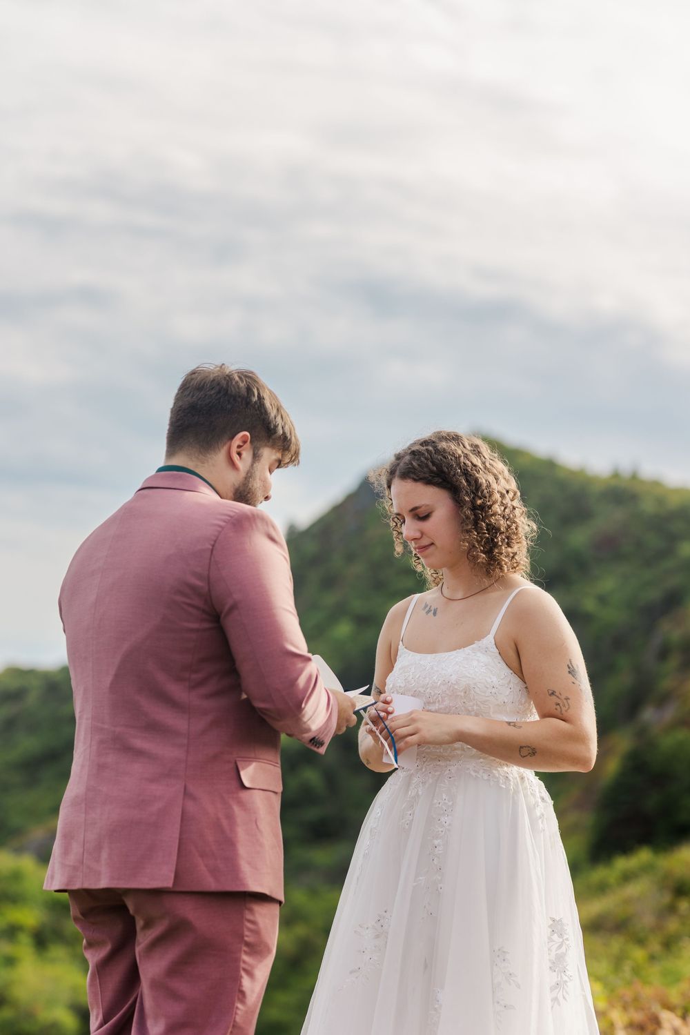 A couple exchanges emotional vows or rings during an intimate outdoor wedding ceremony.