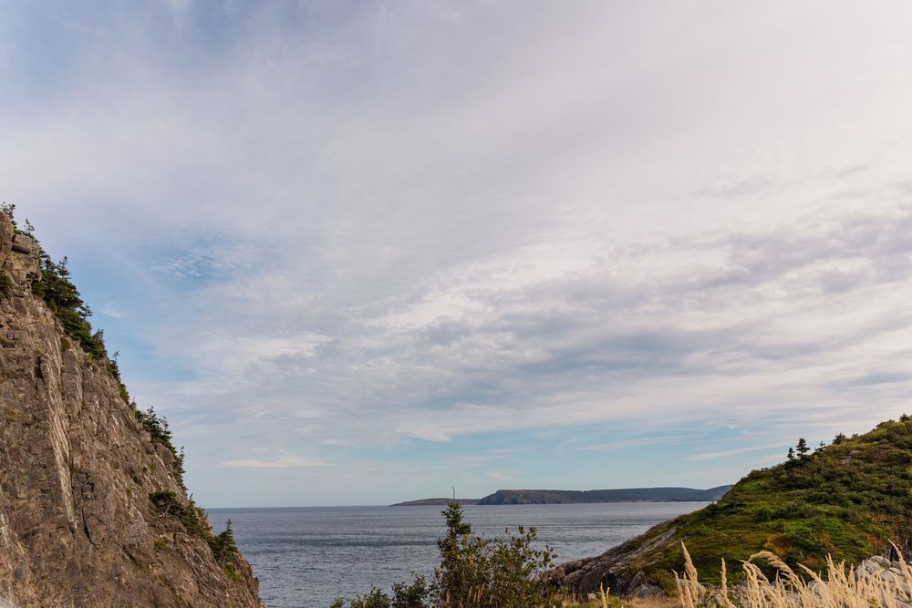 A scenic view of the rugged Nova Scotia coastline with cliffs, hiking trails and the ocean stretching into the horizon.