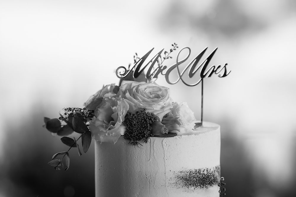 A wedding cake topper with elegant script text reading 'Mr & Mrs' against a blurred background.