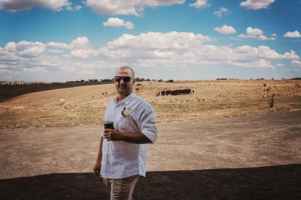 Person stands on arid grassland against blue sky with white clouds on a sunny day.