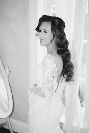 Black and white candid photos capture a bride in a lace wedding gown smiling by a window.