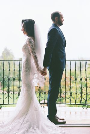Elegant wedding couple poses in creative first look sequence on balcony with ornate railing and scenic backdrop.