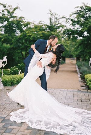 Romantic dip pose sequence of newlyweds on brick pathway with bride's flowing white lace dress trailing behind.
