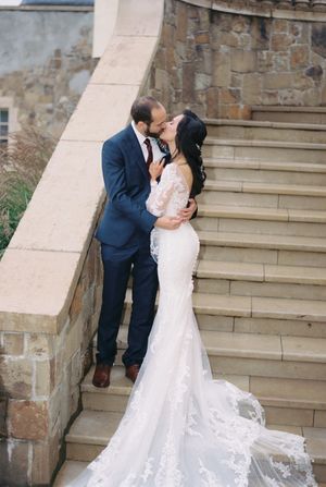 A romantic wedding couple shares an intimate moment while standing together on historic stone steps.