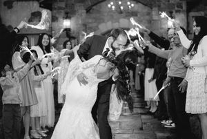 Wedding reception guests dancing and celebrating in a rustic venue with dramatic lighting.