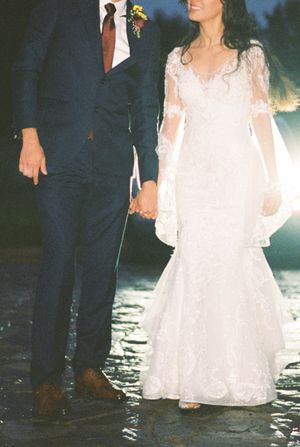 Wedding couple standing in shallow water with their formal attire getting wet during sunset photoshoot.