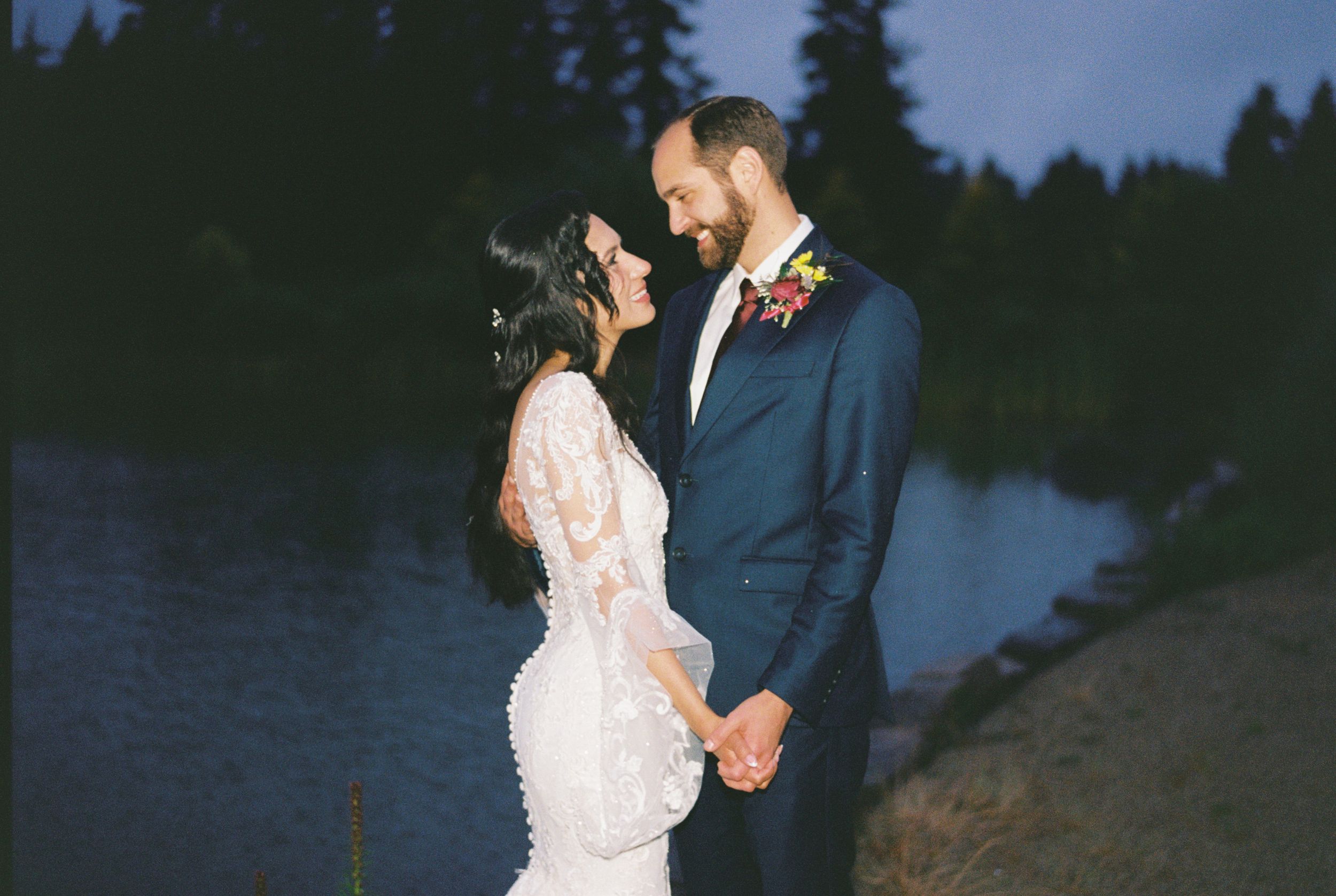 Wedding couple shares romantic moments against forest backdrop during blue hour.