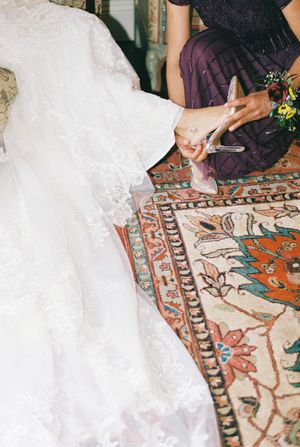 Close-up shot of white wedding dress train details laid out on a vintage patterned oriental rug.