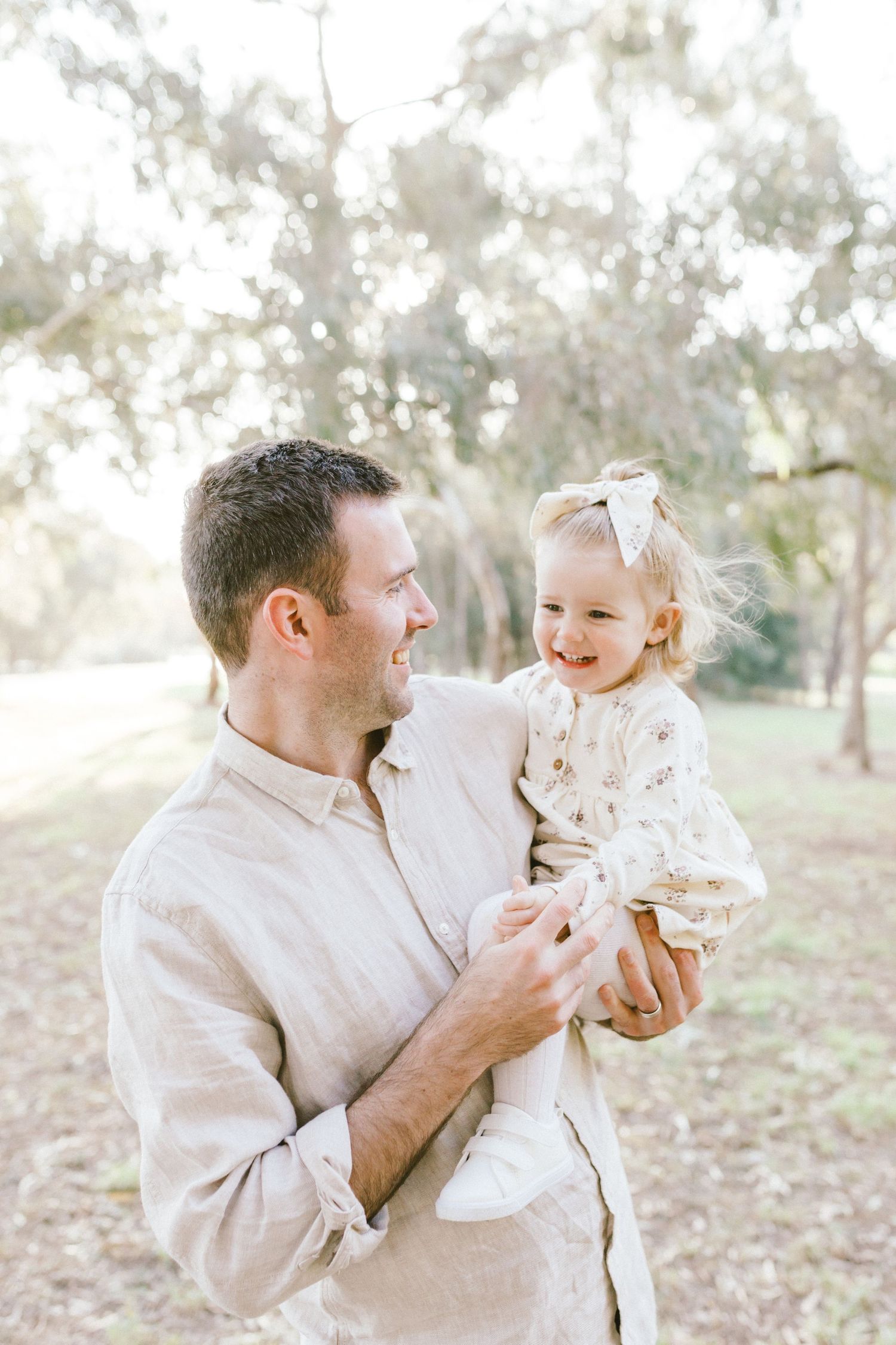 A tender moment captured outdoors as parent and child share a joyful interaction in soft natural lighting.