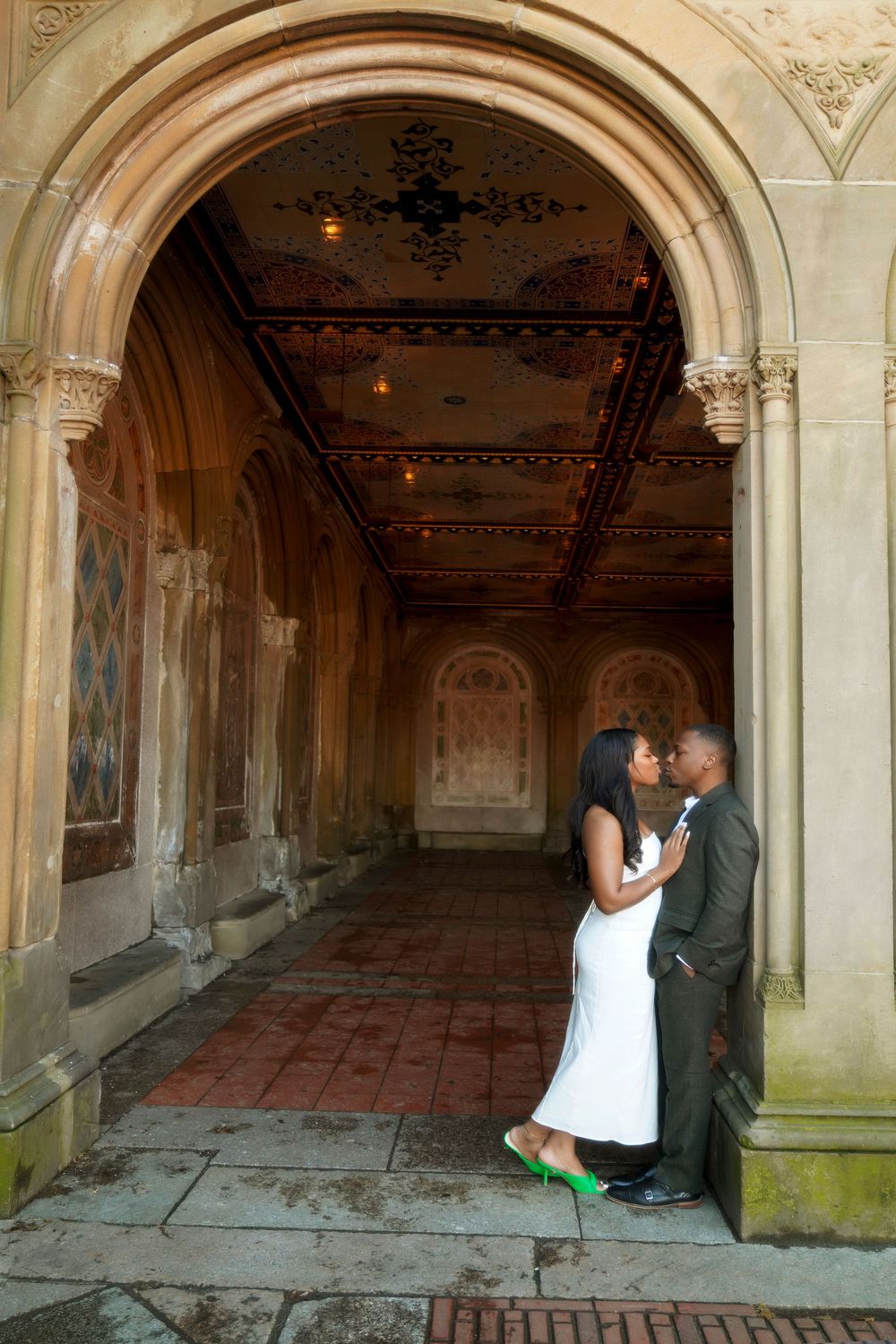 An intimate moment captured in a historic arched hallway with ornate architecture and decorative ceiling details. Bethesda Terrace