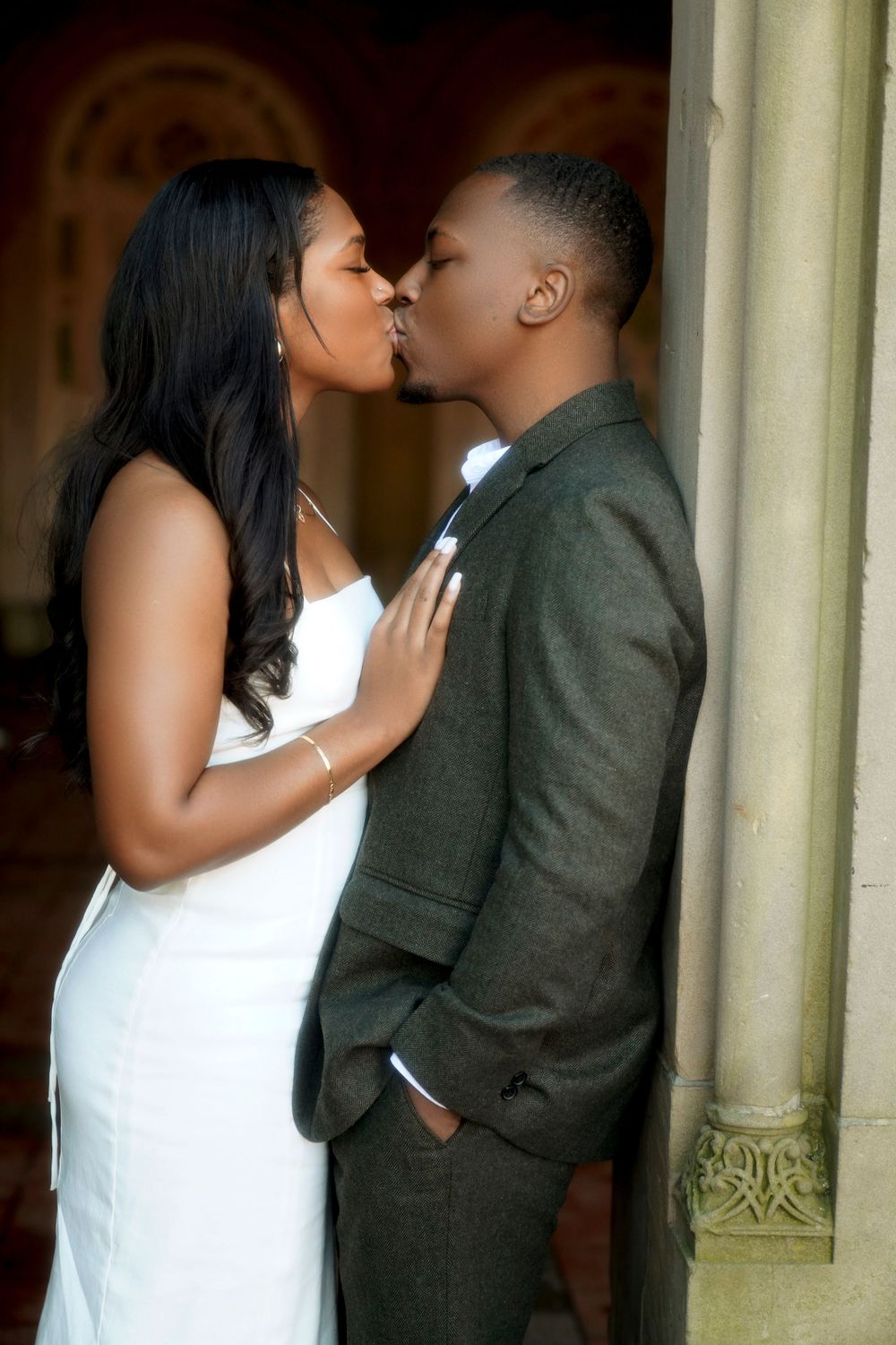 A tender wedding moment captured in multiple sequential photos showing the couple sharing a romantic kiss against stone pillars.