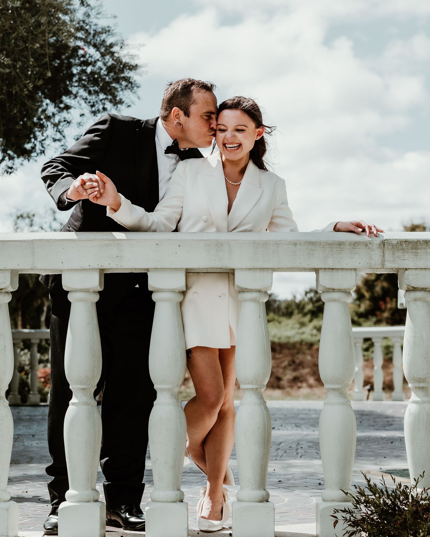Couple interacting playfully on wooden benches in an outdoor garden setting.