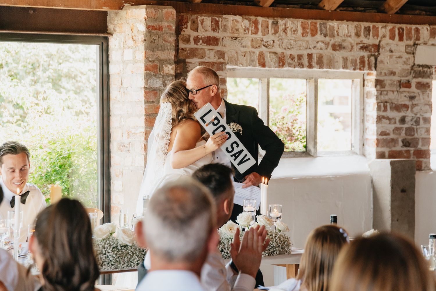 Wedding reception in rustic brick venue with exposed beams and natural lighting.